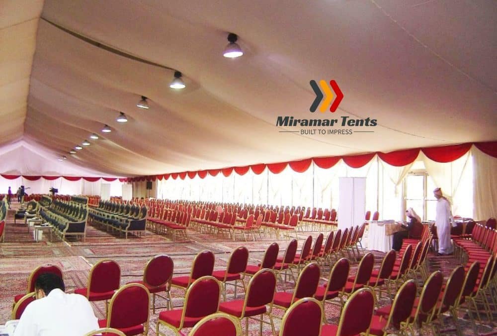 A large event tent houses rows of red and black chairs, perfectly arranged for a gathering. On the wall, the Miramar Tents logo proudly stands out, setting the tone for what's sure to be a memorable occasion.
